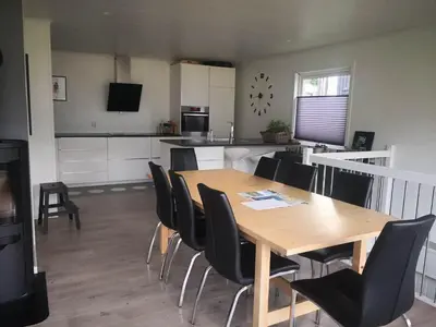 a dining room and kitchen with a wooden table and chairs at Koselig hus med flott utsikt in Vossevangen