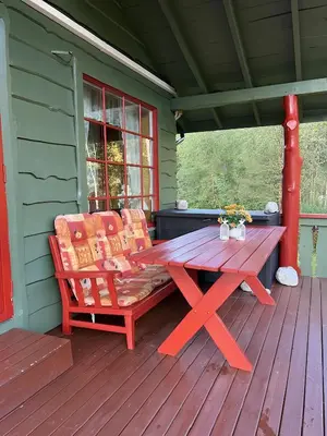 a red picnic table on the porch of a house at Storevatn Fritid in Masfjorden