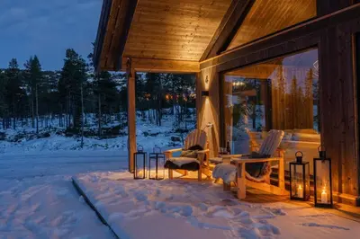a cabin in the snow with two chairs and lights at Luxury holiday home, skiing, sauna, remote office in Nesbyen