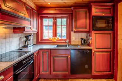 a kitchen with red wooden cabinets and a sink at Lisetra 716A in Trysil