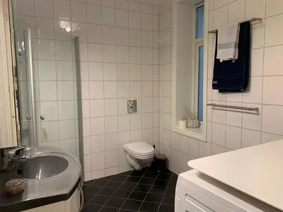 a white bathroom with a toilet and a sink at Stay centrally in a charming and peaceful neighborhood in Bergen