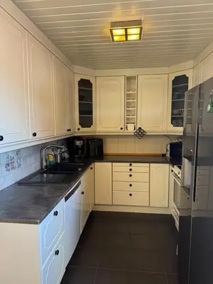 a kitchen with white cabinets and a black refrigerator at Sentral familievennlig enebolig in Åmot