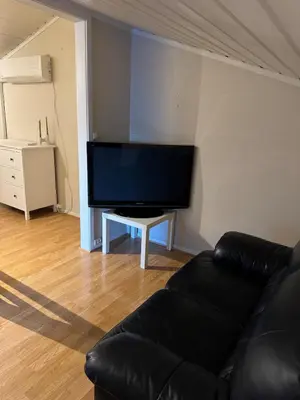 a living room with a black couch and a flat screen tv at Sentral familievennlig enebolig in Åmot