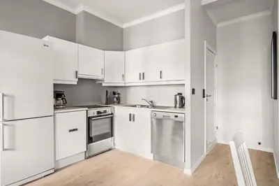 a kitchen with white cabinets and stainless steel appliances at Bergen Beds Apartments - A Front Row Experience in Bergen