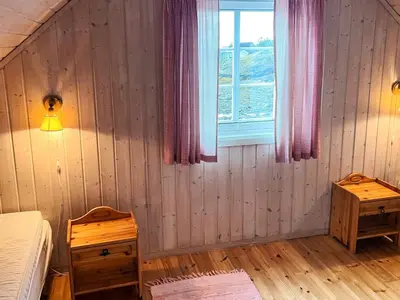 a bedroom with a bed and a window and wooden floors at Seaside Retreat with Boats & Fishing in Brekstad