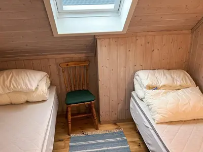 a room with two beds and a chair and a window at Seaside Retreat with Boats & Fishing in Brekstad
