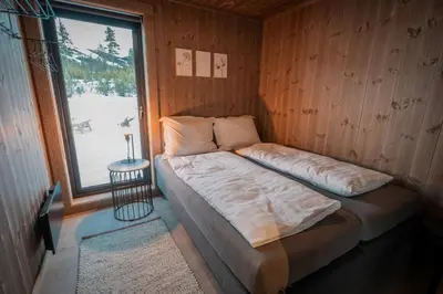 a bed in a room with a large window at Tiur, stylish new cabin with hot tub in Nesbyen