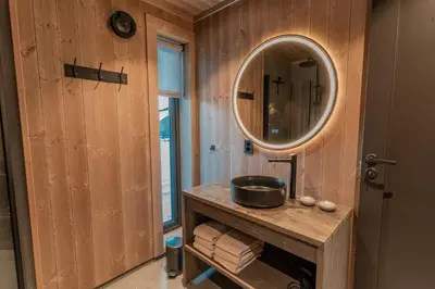 a bathroom with a mirror and a wooden wall at Tiur, stylish new cabin with hot tub in Nesbyen
