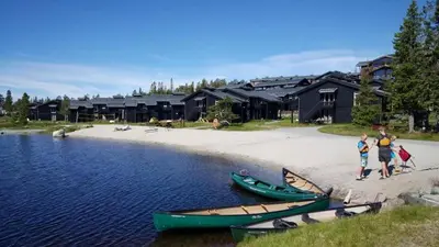 a group of people standing on a beach with two boats at Robelia - Sauna, Hot tub - Norefjell ski center in Noresund