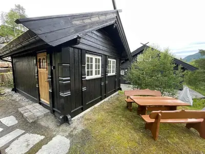 a small black building with a picnic table and a bench at Small cabin at Seljestad in Utsikten