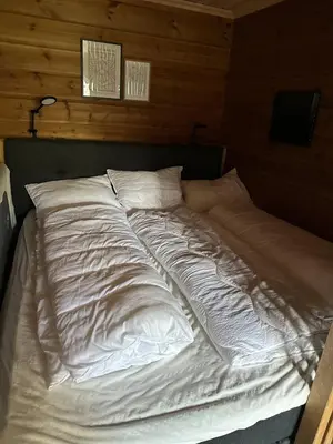 an unmade bed with white sheets and pillows at Small cabin at Seljestad in Utsikten