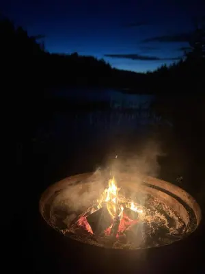 a fire in a metal pot at night at Cozy lakeside cabin in Trøndelag