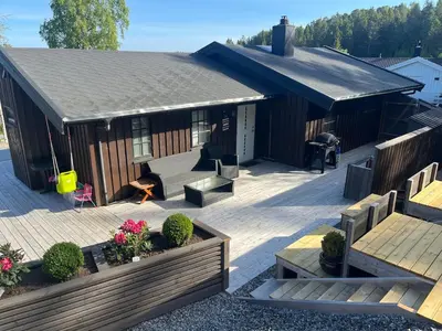 a house with a deck with a table and benches at Cottage by the lake in Namsos in Fosslandsosen