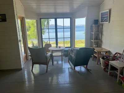 a living room with chairs and a table and windows at Cottage by the lake in Namsos in Fosslandsosen