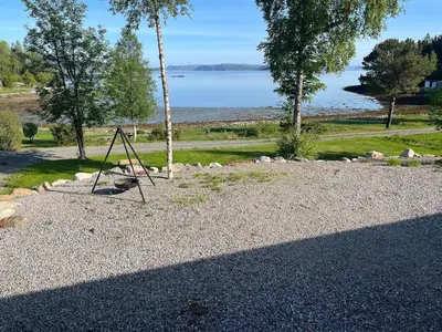 a tree swing sitting on the gravel near the water at Cottage by the lake in Namsos in Fosslandsosen