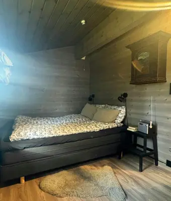 a bed in a room with a wooden wall at Cosy Family Cabin With Views And Sauna in Svingvoll