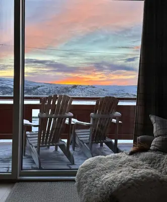 two chairs sitting on a balcony with a sunset at Beautiful apartment at Ustaoset in Hol