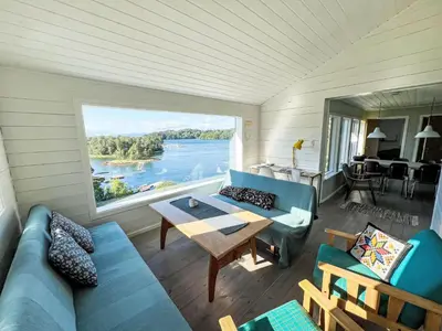 a living room with a couch and a table and a large window at Holiday Home Lauvlid Cottage by Interhome in Tysnes