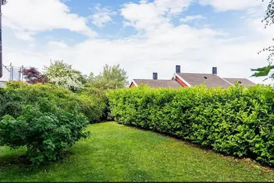 a garden with green bushes and a house at Large and bright apartment, perfect base in autumn in Ålesund