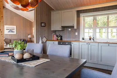 a kitchen with a wooden table with chairs and a dining room at Valdreshytte med peis Klassisk og lun stil in Aurdal