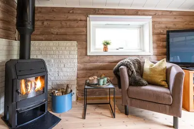 a living room with a fireplace and a chair and a television at The Blue Cabin in Trysil