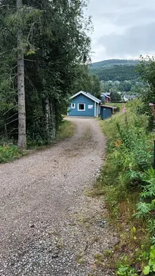 a gravel road with a blue house in the distance at The Blue Cabin in Trysil