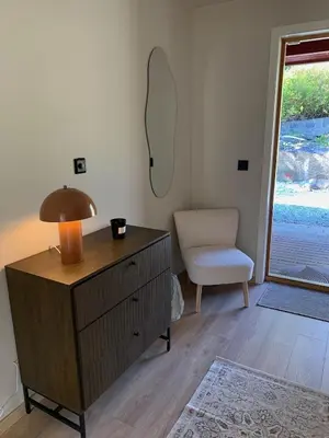 a room with a dresser and a lamp and a chair at Bright and nice apartment in Kristiansund