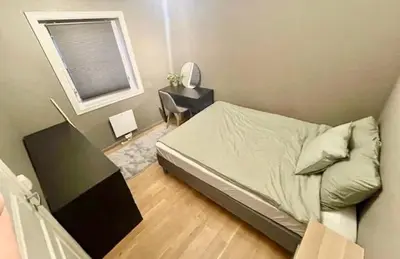 a bedroom with a bed and a table and a window at Koselig leilighet ved Solsiden in Trondheim