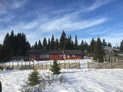 a red house in the snow with a fence at Very central and by the lake Sjusjøen in Ringsaker