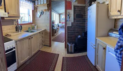 a kitchen with wooden cabinets and a white refrigerator at Very central and by the lake Sjusjøen in Ringsaker