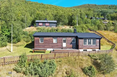 a log cabin on a hill with a bench in front at Fjellro-Geilo Cabin Retreat in Geilo