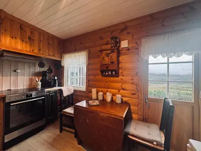 a kitchen with wooden walls and a table and a window at Fjellro-Geilo Cabin Retreat in Geilo