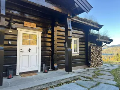 a wooden cabin with a white door and windows at Log cabin at Hafjell in Øyer