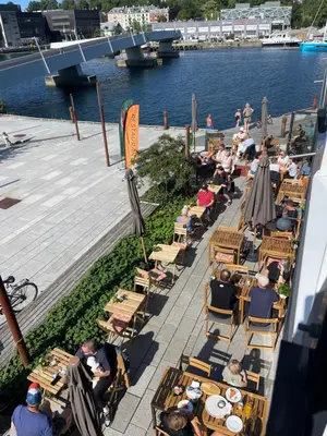 a group of people sitting at tables near the water at Sentrumsnær leilighet Bergen in Bergen