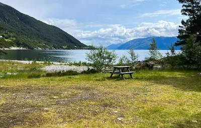 a picnic table sitting in the grass next to a lake at Gorgeous Home In Lavik With House Sea View in Lavik