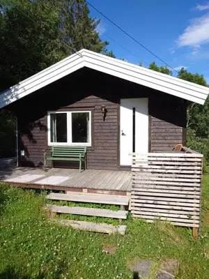 a small cabin with a bench on a wooden deck at Mountain view cabin in Torvik