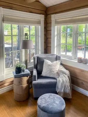 a living room with a blue chair and windows at Log Cabin With Panoramic Views At Voss Resort in Skulestadmo