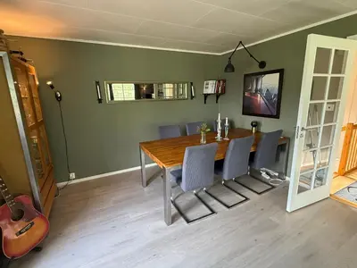 a dining room with a table and chairs and a guitar at Vistdal Panoramic View in Myklebostad