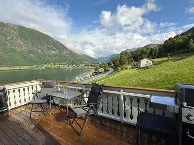 a balcony with a table and chairs and a view of a river at Vistdal Panoramic View in Myklebostad