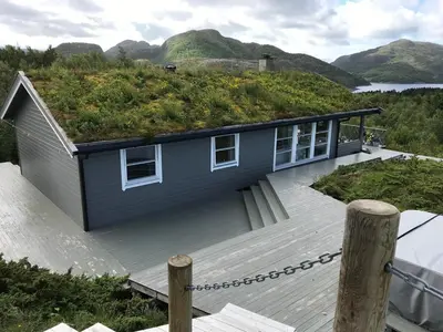 a house with a grass roof with a deck at Cabin with stunning views and outdoor jacuzzie in Leset
