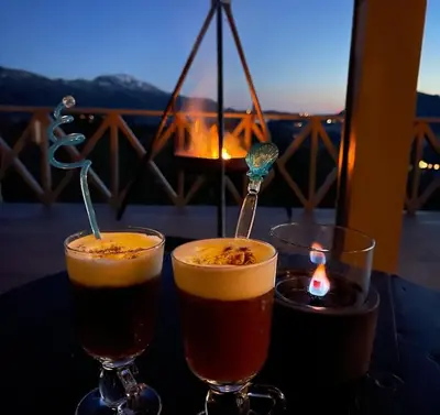two glasses of beer sitting on a table with a candle at Cabin with stunning views and outdoor jacuzzie in Leset