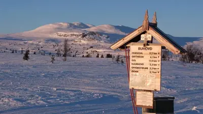 a sign in the snow with a mountain in the background at Nydelig hyttetun på Torpoåsen in Torpo