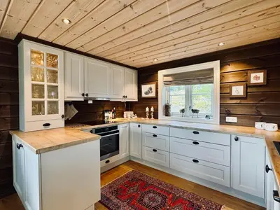 a kitchen with white cabinets and a wooden ceiling at Spacious cabin in the mountains in Gol