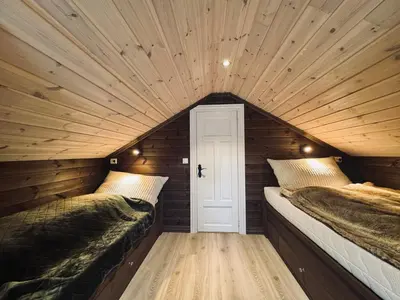 two beds in a room with wooden walls at Spacious cabin in the mountains in Gol