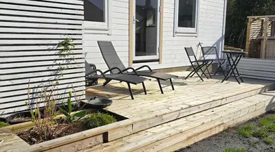 a deck with chairs and a table on a house at Modern City Apartment with garden and view in Molde