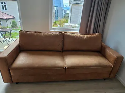 a brown couch sitting in front of a window at Modern City Apartment with garden and view in Molde