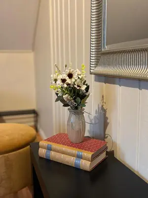 a vase of flowers on a table with books at 3 soveroms leilighet-komfort og stil -perfekt for ferie og jobb in Gjøvik
