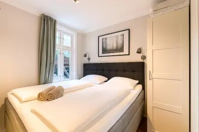 a bedroom with a large bed with white sheets at Apartment Bergen Center - Quiet Gem - Norwegians Minimum Age 25 in Bergen