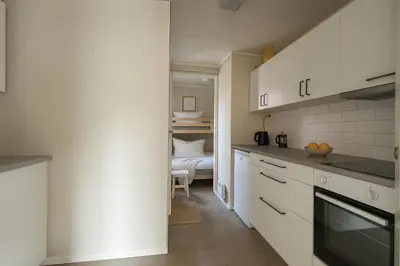 a kitchen with white cabinets and a bed in the background at Twin Flats 1st Floor in Bergen Centre - Norwegians Minimum Age 25 in Bergen