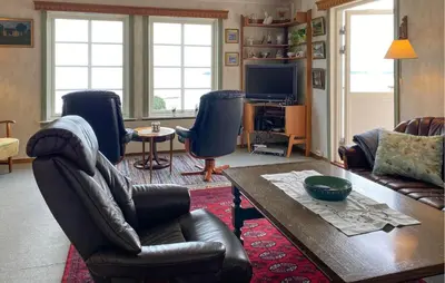 a living room with chairs and a table and a television at Lovely Home In Fiksdalen in Fiksdal